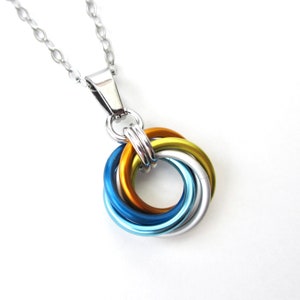 May include: A silver chain necklace with a multi-colored knot pendant. The knot is made of four intertwined wires in shades of blue, green, and gold.