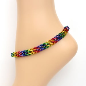 May include: Rainbow colored metal chain anklet. The anklet is made of small, linked rings in a rainbow pattern.