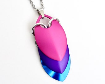 May include: A layered heart pendant necklace with a pink, purple, and blue color scheme. The pendant is made of metal and has a silver chain.