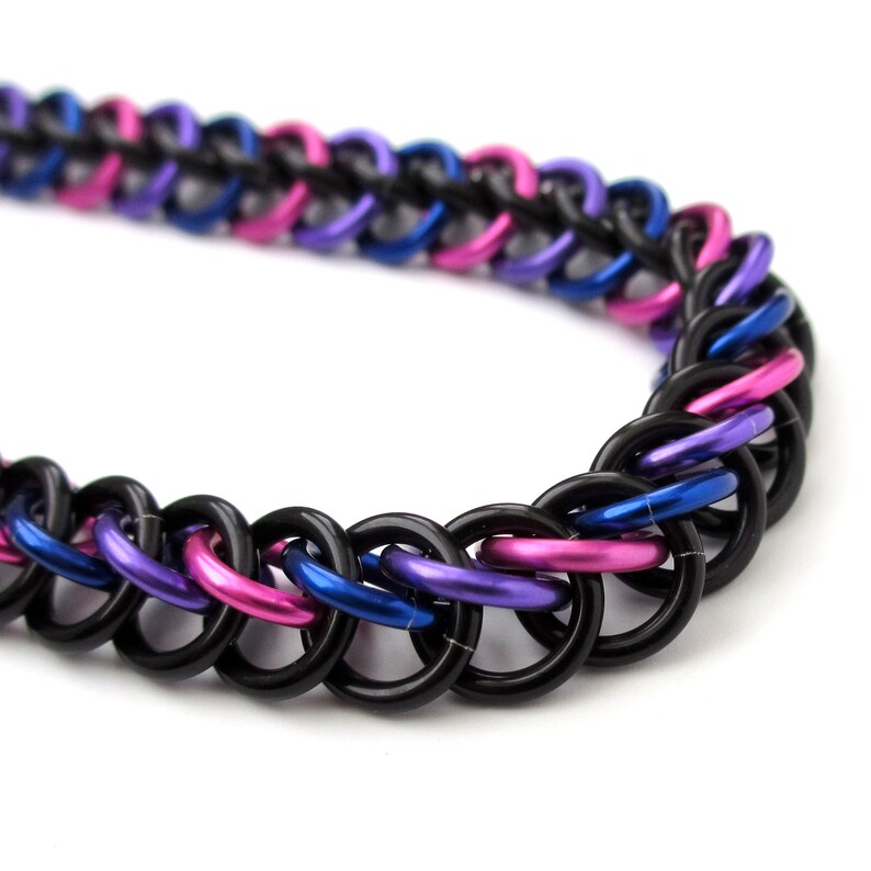 May include: A black, blue, and pink chainmail bracelet. The chainmail is made of small metal rings that are linked together.