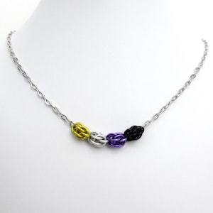 May include: A silver chain necklace with a series of woven beads in yellow, white, purple, and black.