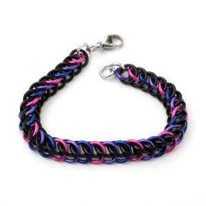 May include: A black, pink, and blue chainmail bracelet with a silver clasp.