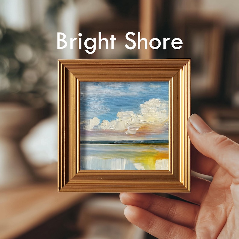 May include: A small framed painting with a gold-colored frame. The artwork depicts a seascape with a blue sky, white clouds, and a reflective body of water. The text "Bright Shore" is displayed at the top of the frame.