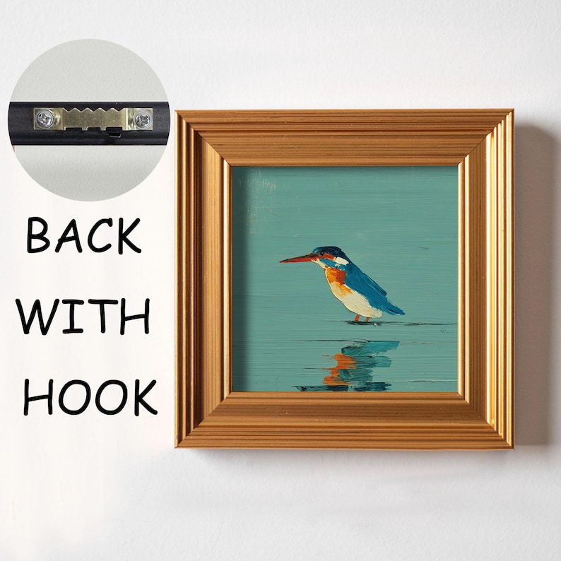May include: Square framed art print featuring a colorful bird with a long beak standing in water. The bird has blue, white, and orange feathers. The frame is gold-colored. The back of the frame has a hook for hanging.