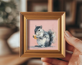 May include: A framed painting of a gray and white squirrel holding a yellow object, set against a pink background. The artwork is in a gold-colored frame. The painting has a textured, brushstroke style.