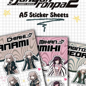 Può includere: Fogli di adesivi A5 con personaggi di Danganronpa 2: Goodbye Despair. I fogli presentano più adesivi di Chiaki Nanami, Mikan Tsumiki e Nagito Komaeda. Lo sfondo è un motivo a griglia con elementi decorativi.