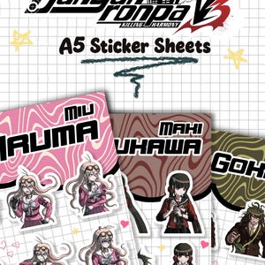 Puede incluir: Hojas de pegatinas A5 con personajes de Danganronpa V3 Killing Harmony. Las hojas muestran a Miu Iruma, Maki Harukawa y Gonta Gokuhara en varias poses. El fondo es una cuadrícula blanca con patrones ondulados rosas, marrones y verdes.