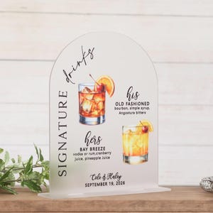 May include: An arched clear acrylic sign featuring the text SIGNATURE drinks, his OLD FASHIONED, and hers BAY BREEZE with illustrations of two cocktails, plus the names Cole & Haley and the date SEPTEMBER 19, 2026 printed in black ink.