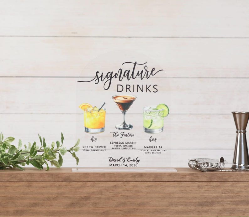 May include: An arched clear acrylic sign titled Signature Drinks featuring watercolor illustrations of a screwdriver, espresso martini, and margarita. Text includes The Fosters, David & Emily, March 14, 2026, and ingredient lists for each cocktail.