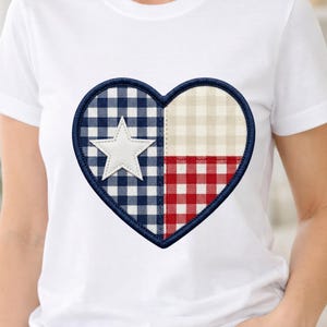 May include: White t-shirt featuring a heart-shaped design with a Texas flag theme. The heart is divided into sections with a white star, blue and white gingham, beige and white gingham, and red and white gingham.