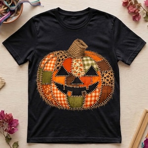 Puede incluir: Una camiseta negra de manga corta con un gran gráfico central de una calabaza hecha de varios parches de tela. El diseño de la calabaza incluye patrones de cuadros naranjas, verdes y marrones, estampado de leopardo y motivos florales.