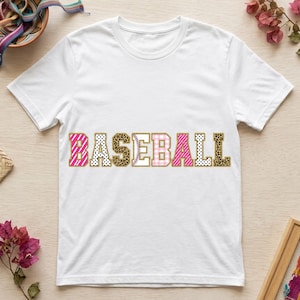 Puede incluir: Una camiseta blanca de manga corta con la palabra BASEBALL impresa en el pecho. Cada letra tiene un patrón único, incluyendo rayas rosas, lunares blancos y negros, estampado de leopardo y una textura de pelota de béisbol con costuras.