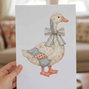 Puede incluir: Ilustración de un ganso con diseño de patchwork. El ganso presenta un lazo azul, patrones florales y de cuadros, y un pico y patas de color naranja claro. La obra de arte está sostenida por una mano.