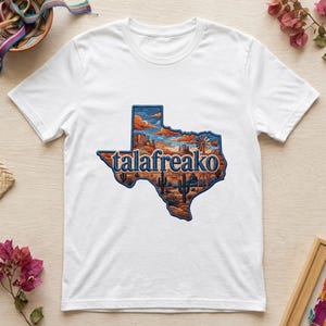 Puede incluir: Una camiseta blanca de manga corta con un gráfico del estado de Texas. El gráfico contiene un paisaje desértico con cactus, un molino de viento y nubes, con la palabra "talafreako" impresa en letras azules en el centro de la forma.