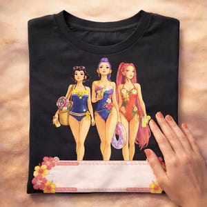 Puede incluir: Camiseta negra con un gráfico de tres mujeres en trajes de baño, cada una con accesorios de playa. Las mujeres tienen diferentes colores de cabello y diseños de trajes de baño. Una pancarta floral está en la parte inferior.