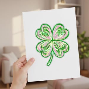 Puede incluir: Un papel blanco con una ilustración de un trébol de cuatro hojas. El trébol está en tonos de verde, rosa y amarillo, con un contorno verde. La obra de arte tiene un aspecto pintado.