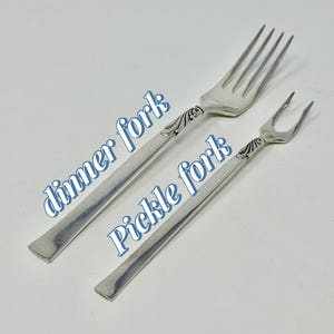 May include: Two silver forks, a dinner fork and a pickle fork, are displayed against a white background. The dinner fork has four tines, while the pickle fork has two. The text "dinner fork" and "Pickle fork" are superimposed on the image.