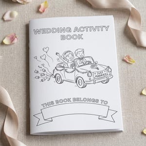 May include: A white wedding activity book with black line art. The cover features the text "WEDDING ACTIVITY BOOK" and an illustration of a newlywed couple in a car. The bottom reads "THIS BOOK BELONGS TO".