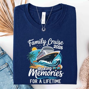 May include: Navy blue t-shirt with a cruise ship graphic and the text "Family Cruise 2026 Making Memories for a Lifetime." The design includes a cruise ship, palm tree, beach, sunglasses, and a beach ball. A silver necklace with a sun pendant is on top.
