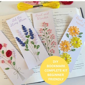 May include: Four white rectangular bookmarks featuring embroidered floral designs in red, pink, blue, purple, and yellow thread. The bookmarks include text reading Let the Story Bloom, Read and Wander, and Read, repeat. A yellow circle overlay reads DIY BOOKMARK COMPLETE KIT BEGINNER FRIENDLY.