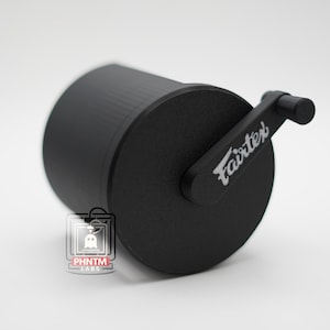 Puede incluir: Un objeto cilíndrico negro con un asa, con el texto blanco "Fairtex". El objeto tiene una superficie texturizada y parece ser de metal. El diseño general es elegante y moderno, adecuado para una variedad de usos.