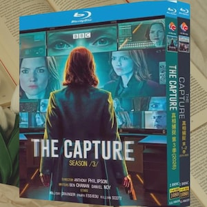 Puede incluir: Un set de discos Blu-ray de "The Capture" Temporada 3. La portada presenta a una mujer con un abrigo oscuro, con el título y el número de temporada. El logotipo de la BBC es visible, junto con el texto "2 DISC" y "1080".