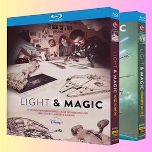 Könnte beinhalten: Zwei Blu-ray-Hüllen für "Light & Magic" mit blauem Deckel und lila Rücken. Das Cover zeigt eine Szene mit Leuten, die an einem Tisch mit einem Raumschiffmodell arbeiten. Das Disney+ Logo ist sichtbar.