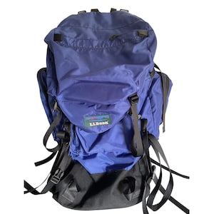 May include: A blue and black LLBean backpack with multiple compartments, straps, and buckles. The backpack has a large main compartment, a front pocket, and side pockets. The LLBean logo is visible on the front.