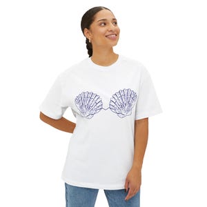 May include: White t-shirt with a blue seashell design. The graphic shows two detailed seashells joined by a line, forming a unique artistic image. The shirt is made of a soft material and has short sleeves.