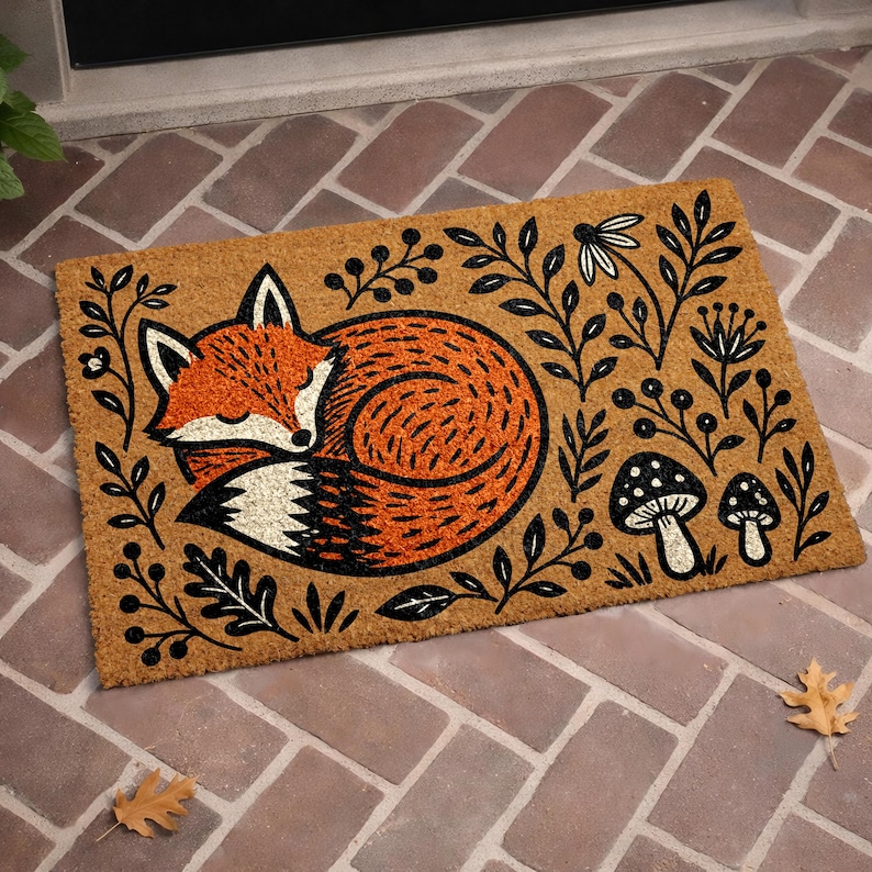 A decorative door mat with a fox curled up and surrounded by leaves, mushrooms, and flowers.