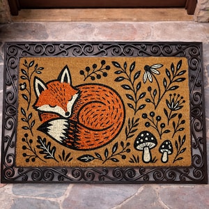 A decorative door mat with a fox curled up and surrounded by various plants and mushrooms.