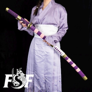 May include: A purple and pink katana sword with gold accents. The handle is wrapped in purple fabric, and the blade is a silver color. The sword is held by a person wearing a purple kimono.
