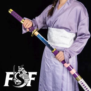 May include: A decorative katana sword with a purple handle and accents, a blue and black blade, and a pink and purple sheath. The sword is held by a person wearing a purple kimono. The logo "FSF" with a samurai is visible.