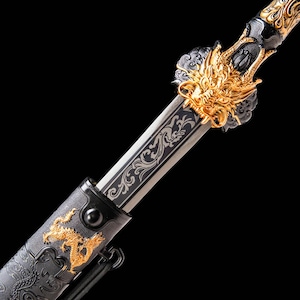 Könnte beinhalten: Ein Schwert mit einer Metallklinge und kunstvollen Rankengravuren. Der Griff ist mit einer detaillierten, goldfarbenen Drachenkopfskulptur verziert. Die schwarze Scheide zeigt ein goldenes Drachenrelief und strukturierte Muster.