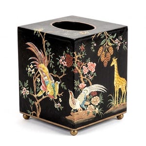 Peut inclure: Boîte à mouchoirs carrée noire avec un motif décoratif représentant des oiseaux colorés, des fleurs et une girafe. La boîte a une bordure dorée et de petits pieds dorés. Le dessus a une ouverture circulaire.