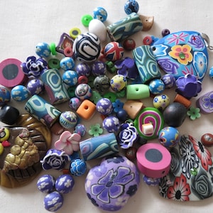 Könnte beinhalten: Eine Sammlung bunter Polymer Clay Perlen und Anhänger in verschiedenen Formen und Größen. Das Sortiment umfasst florale, geometrische und abstrakte Designs mit einer Mischung aus Blau-, Lila-, Grün- und Orangetönen. Maße in cm.