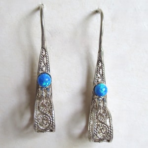 Könnte beinhalten: Ein Paar silberne Filigranohrringe mit blauen Opal-Steinen.