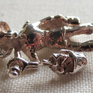 May include: Silver charm of a person carrying a bucket, possibly a construction worker or a miner. The charm is detailed and has a textured surface.