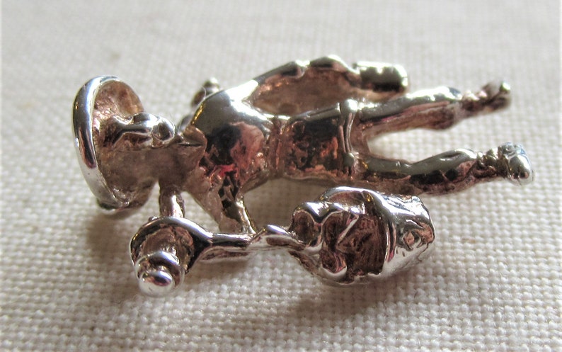 May include: Silver charm of a person carrying a bucket, possibly a construction worker or a miner. The charm is detailed and has a textured surface.