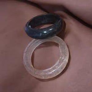 May include: Two rings: one dark blue, the other clear. The dark blue ring is on top of the clear ring. The rings are made of a smooth material and are circular in shape.