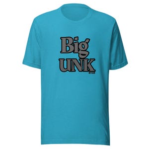 May include: A bright turquoise short-sleeve t-shirt featuring the text Big UNK in large, bold, grey letters with a black outline centered on the chest. Below the text, the smaller words 301 CLUB are printed in a simple black font.