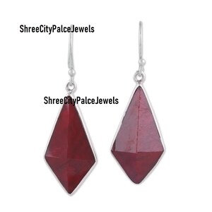 May include: A pair of drop earrings featuring faceted, kite-shaped deep red stones set in silver-toned metal with hook-style findings. The text ShreeCityPalceJewels is visible in the image. The design showcases a geometric, angular silhouette.