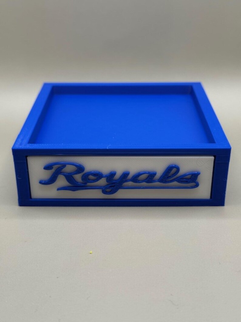 May include: A blue and white box with the word "Royals" in script. The box has a blue interior and a white panel with the word "Royals" in blue script. The box is likely a decorative item or storage container.