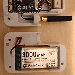 Könnte beinhalten: Ein weißes elektronisches Gerät mit einer schwarzen Antenne und internen Komponenten, darunter eine Leiterplatte, Drähte und ein Akku mit der Aufschrift "3000 mAh". Das Gerät ist geöffnet und zeigt seine innere Struktur.