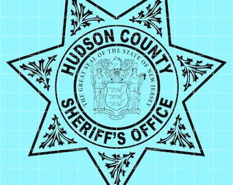 May include: Black and white Hudson County Sheriff's Office badge. The design features a star shape with ornate floral accents. The words "Hudson County Sheriff's Office" are prominently displayed, along with the state seal of New Jersey.