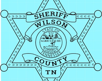 May include: A black and white sheriff badge with the text "SHERIFF WILSON COUNTY TN" and a circular emblem featuring a boat and the words "STATE OF TENNESSEE AGRICULTURE COMMERCE". The badge is a six-pointed star shape.