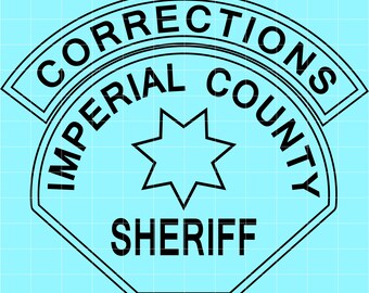 May include: A black and white graphic of a badge with the words "CORRECTIONS IMPERIAL COUNTY SHERIFF" in a semi-circular design. A star shape is in the center of the badge, with a light blue background.