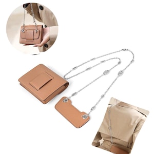 May include: A tan leather-textured rectangular pouch with a matching leather strap attachment, connected by a silver-toned metal chain featuring oval link details. The set includes a small bag and a separate rectangular leather piece for carrying.
