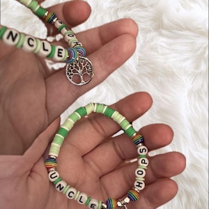 May include: Two handmade bracelets with green and white beads. One bracelet spells "UNCLE" with white letter beads and has a tree of life charm. The other bracelet spells "HOPS" with white letter beads and has a charm.
