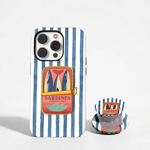 May include: A phone case and phone grip featuring a sardine can design. The case has a blue and white striped background. The sardine can graphic is red with blue fish and the text "Sardines salty but sweet."